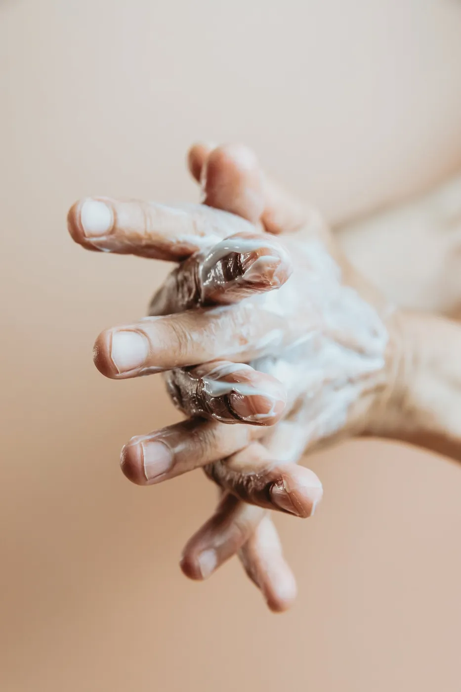 Hand Lather Lotion On In Front Of A Beige Background